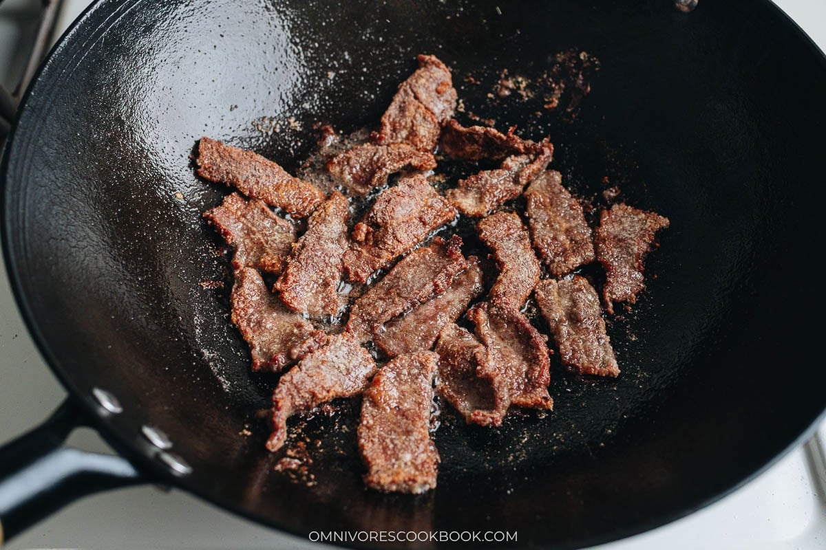 Golden-brown beef slices frying in a wok until crispy.
