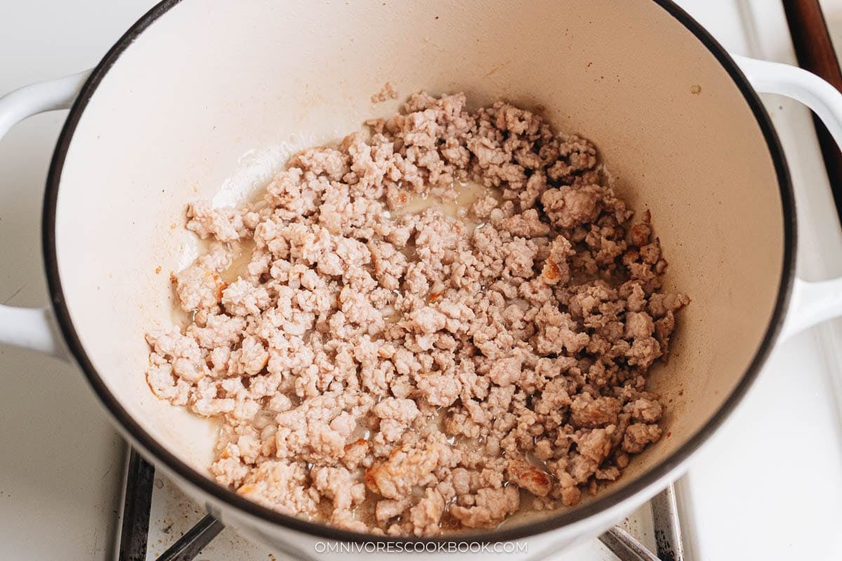 Ground pork browning in a Dutch oven.