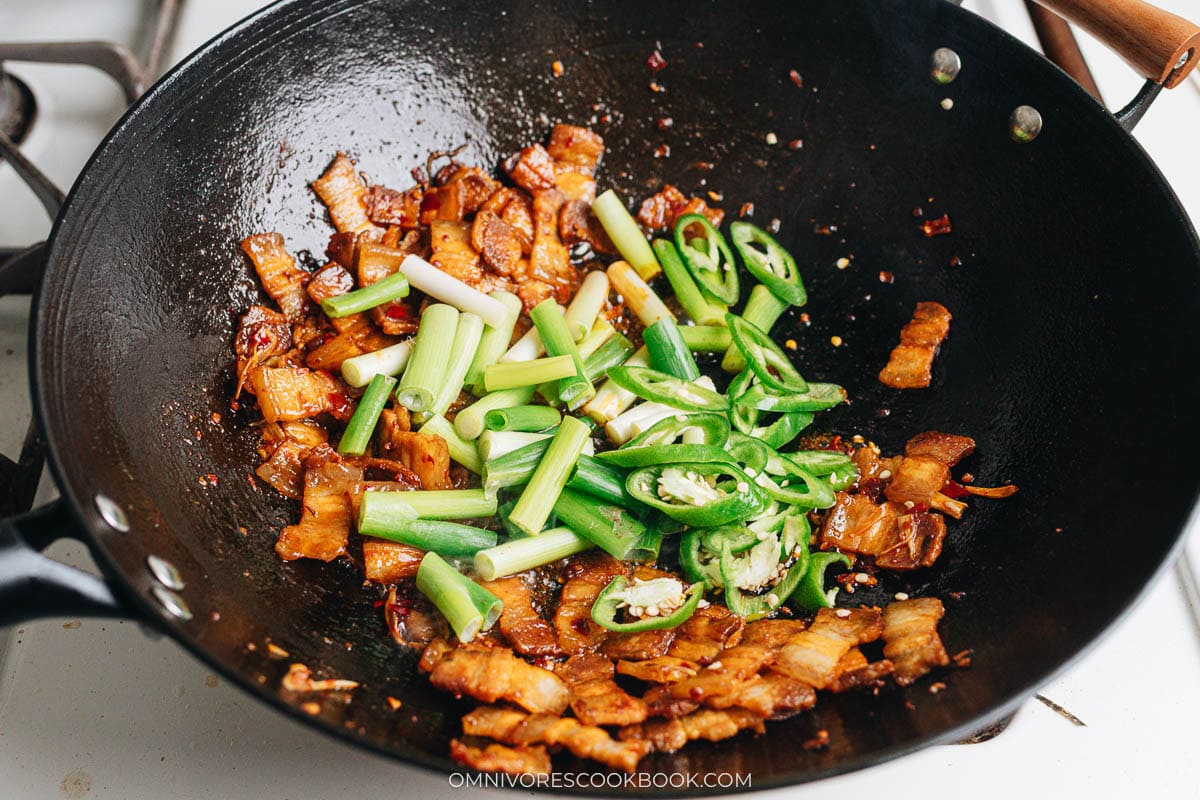 Sliced green onions and green chili peppers added to the wok.