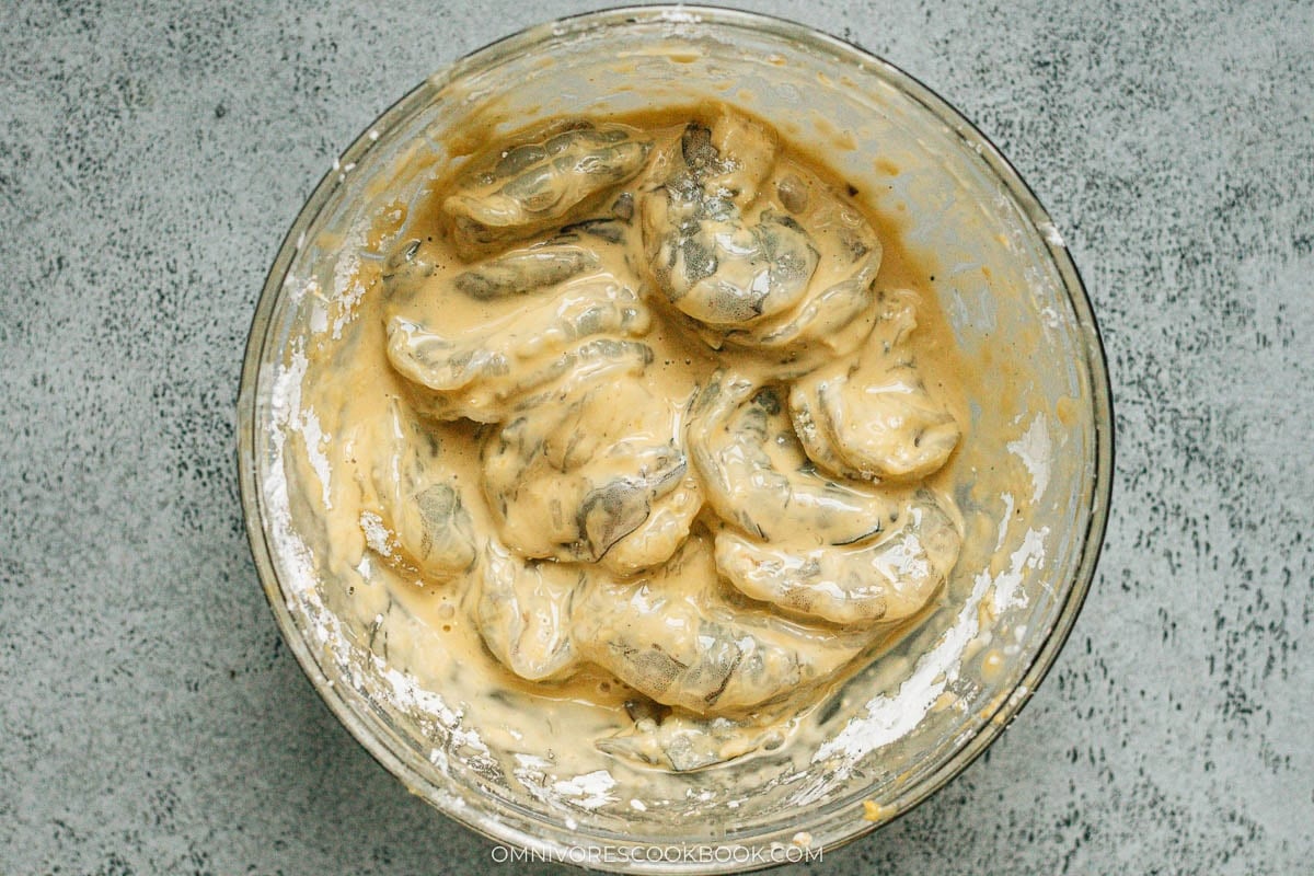 Shrimp coated with a wet batter in a big bowl.
