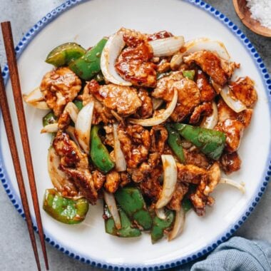 Pork and pepper stir fry plated with chopsticks on the side
