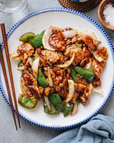 Pork and pepper stir fry plated with chopsticks on the side