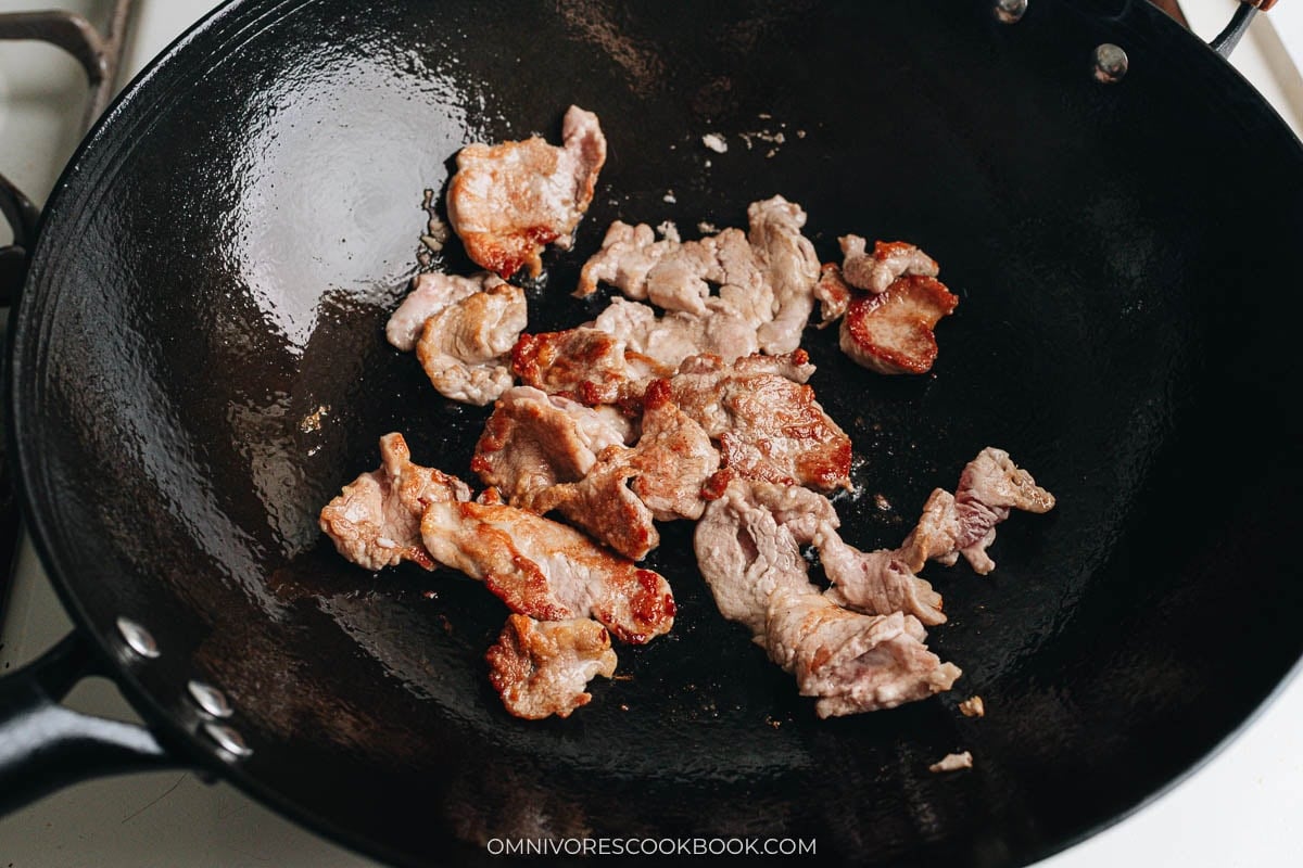 Searing pork slices in a wok