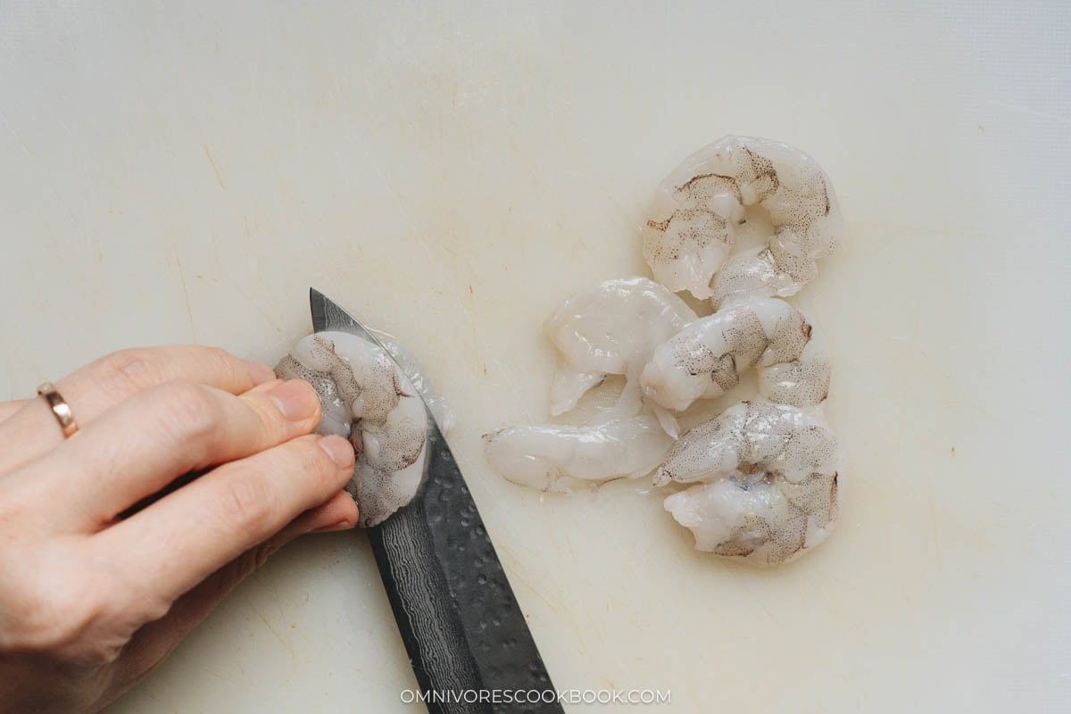 Halving raw shrimp with a knife