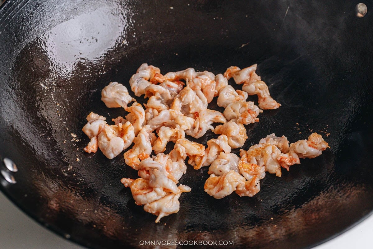Stir frying sliced shrimp in a wok.