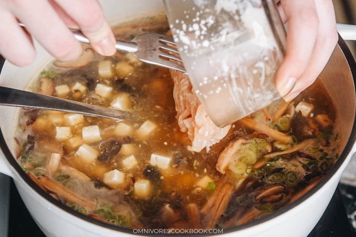 adding marinated pork to the soup