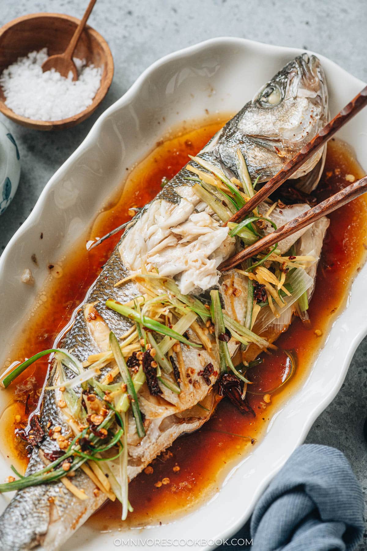 Chinese steamed fish serve on a plate with chopsticks