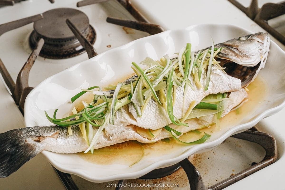 adding julienned ginger and green onions over the fish