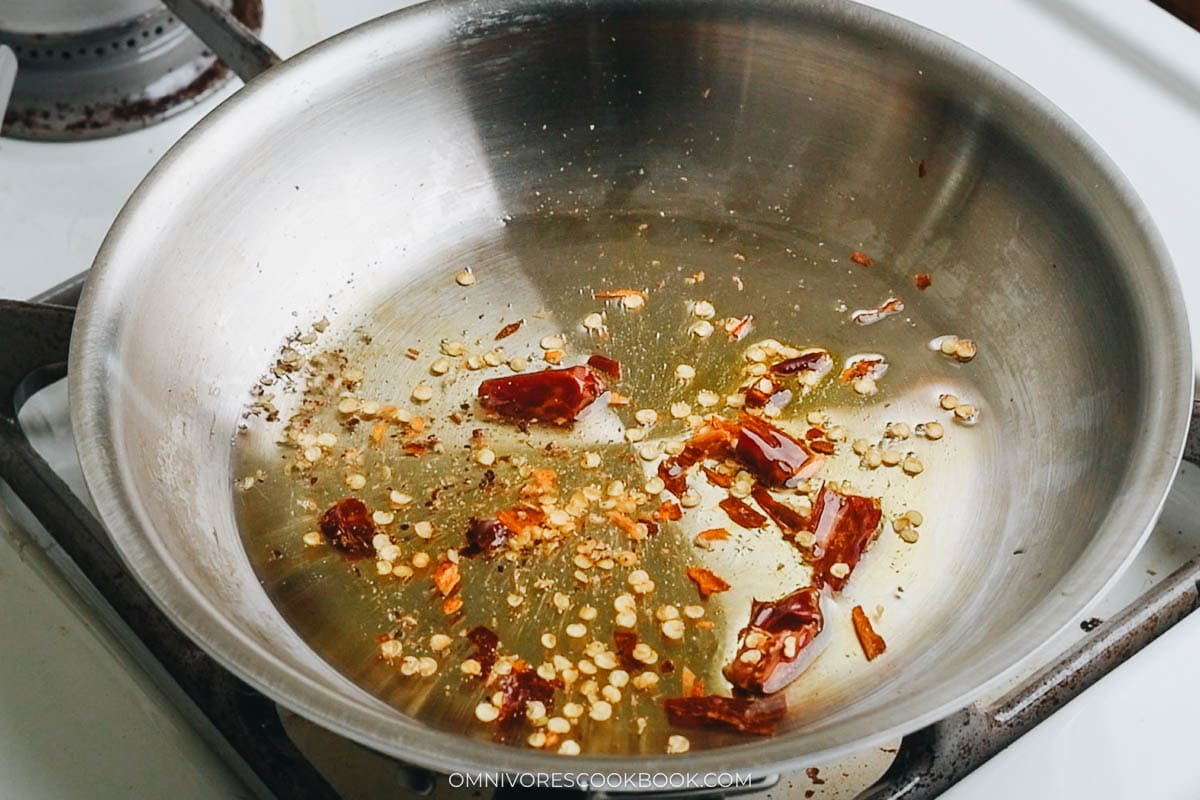 cooking the dried chili peppers and ground Sichuan peppercorns in a small pan