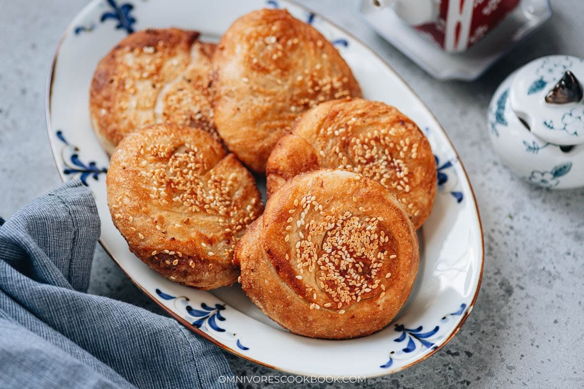 Sesame-crusted juntun guo kui stacked on a plate, pan-fried and baked