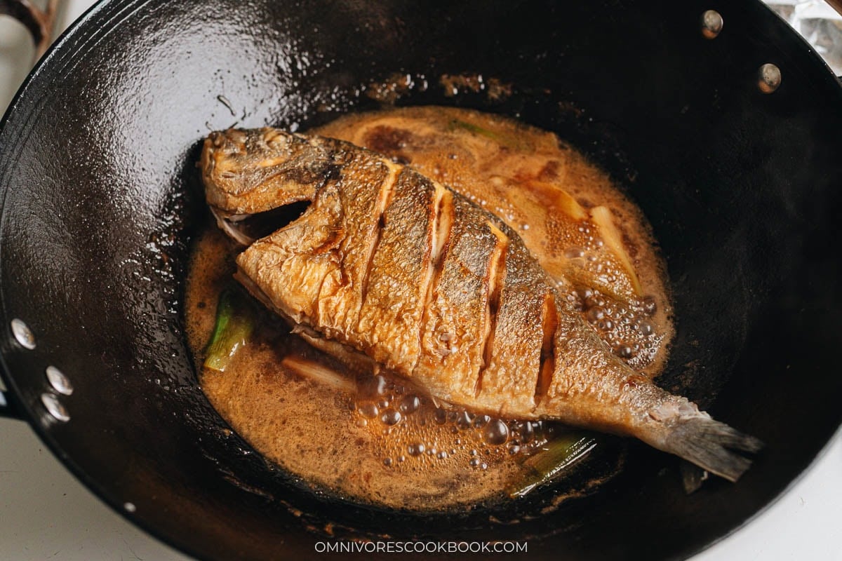 Whole fish braised with soy sauce glaze in a wok