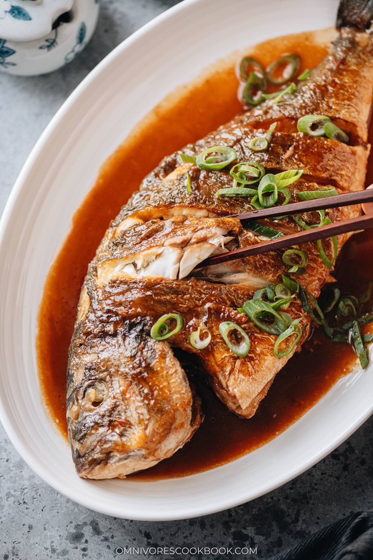 Tender braised whole fish with chopsticks lifting flaky white meat