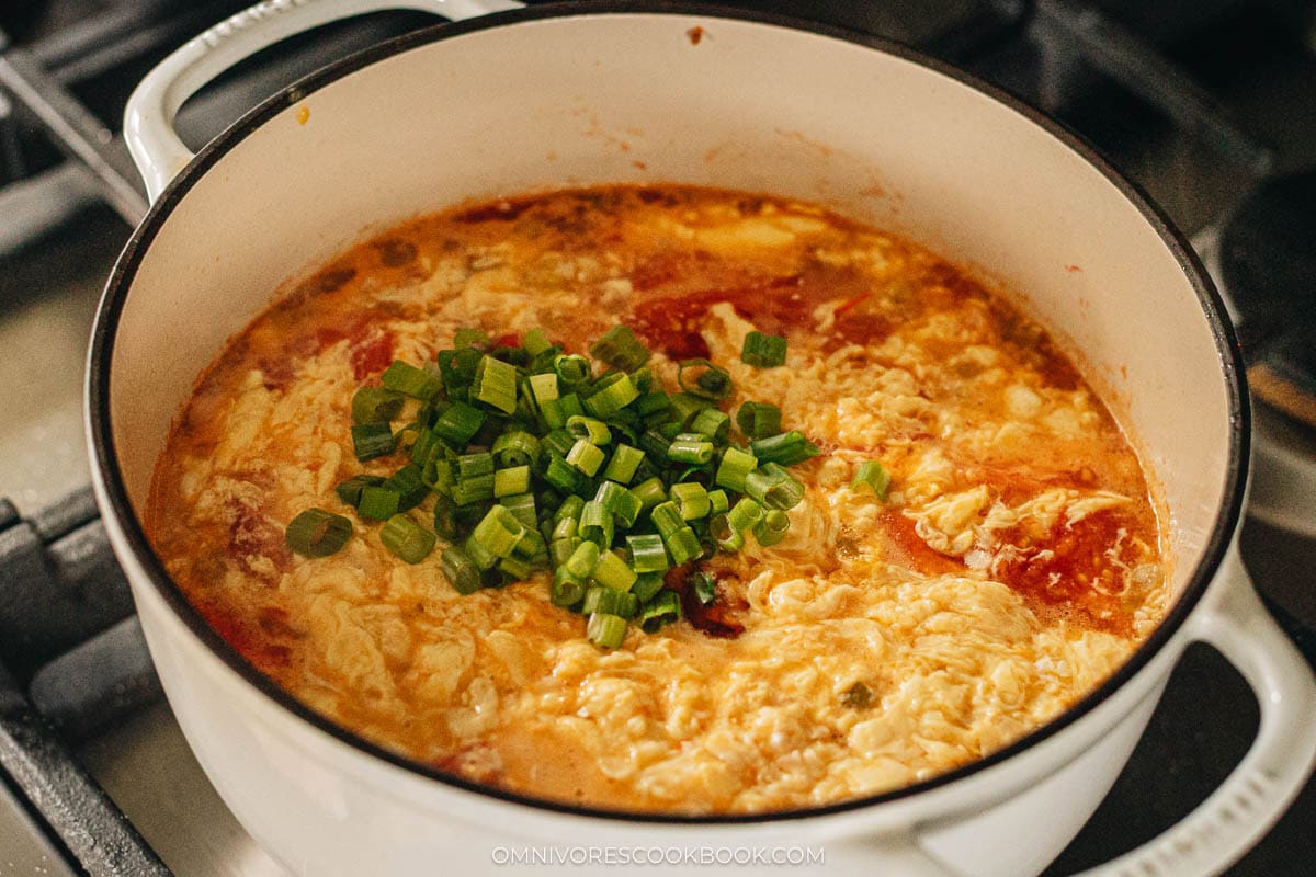 tomato egg drop soup with green onions in a pot