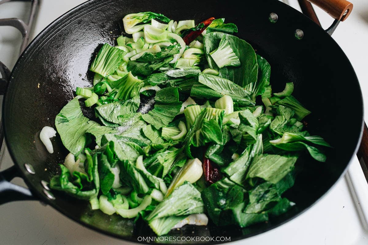Cooking bok choy greens in a hot wok