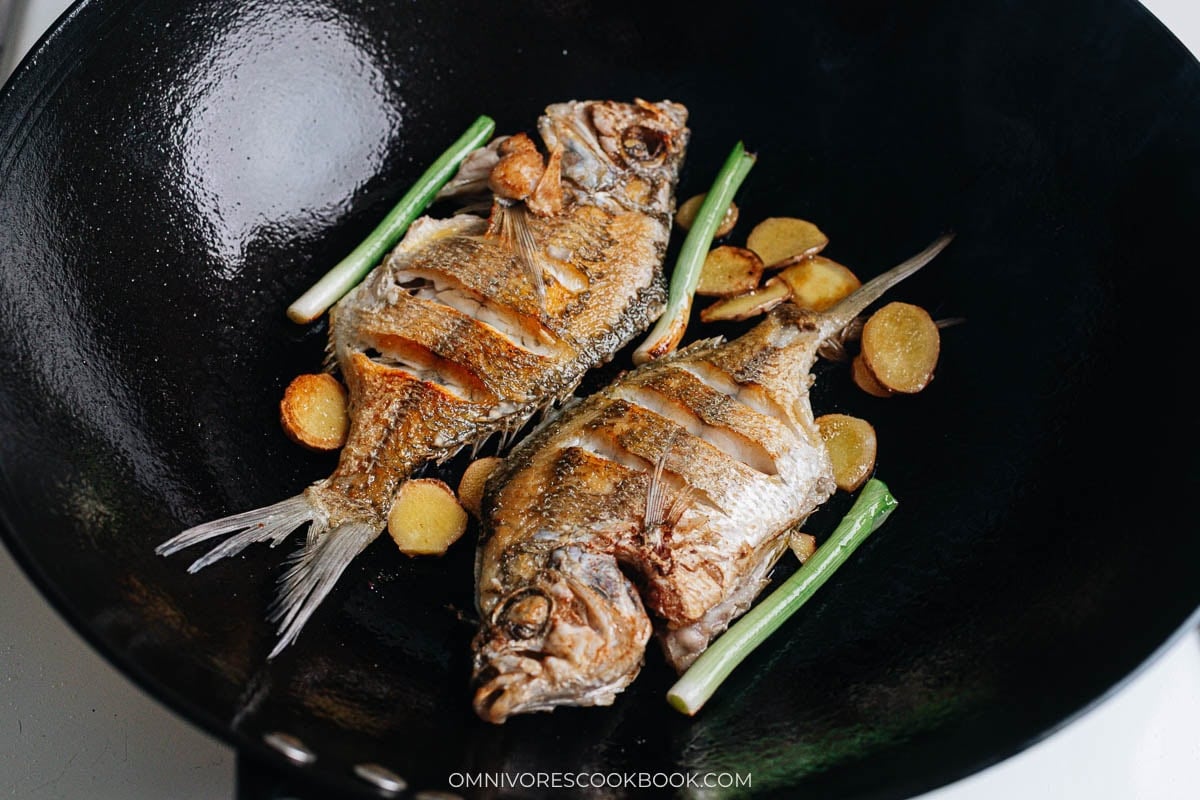 Pan fried fish with ginger and scallions in wok