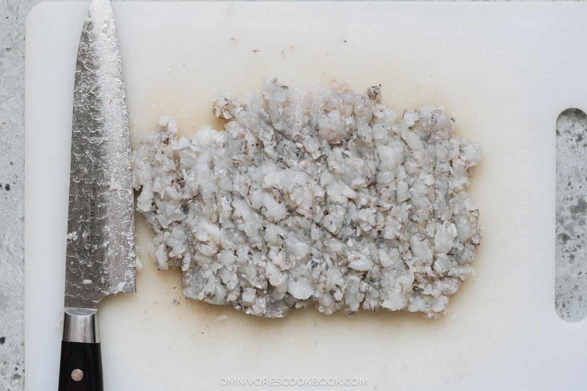 Raw shrimp finely chopped on cutting board