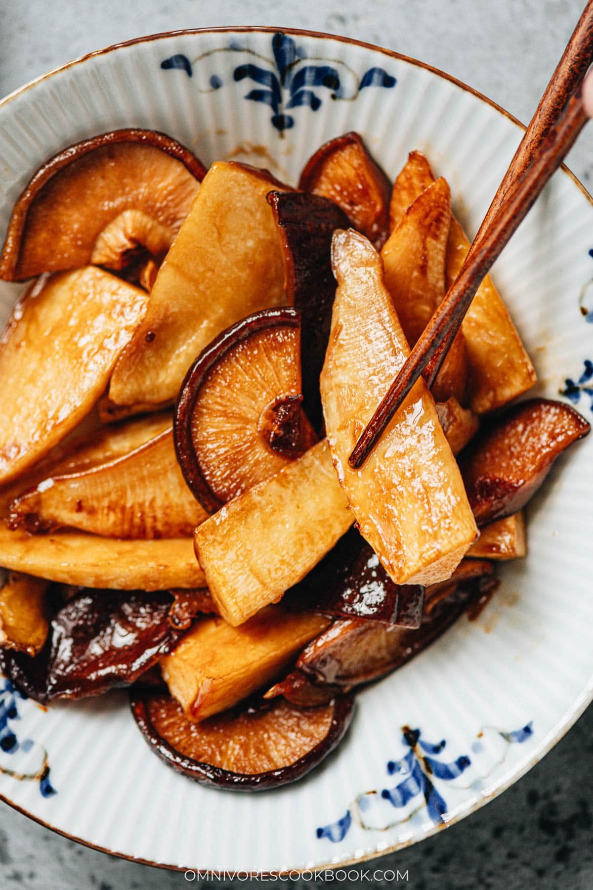 Close-up of lifting bamboo shoots coated in glossy braising sauce