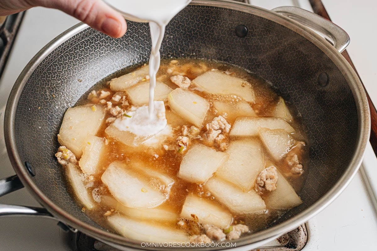 Pouring cornstarch slurry into the wok