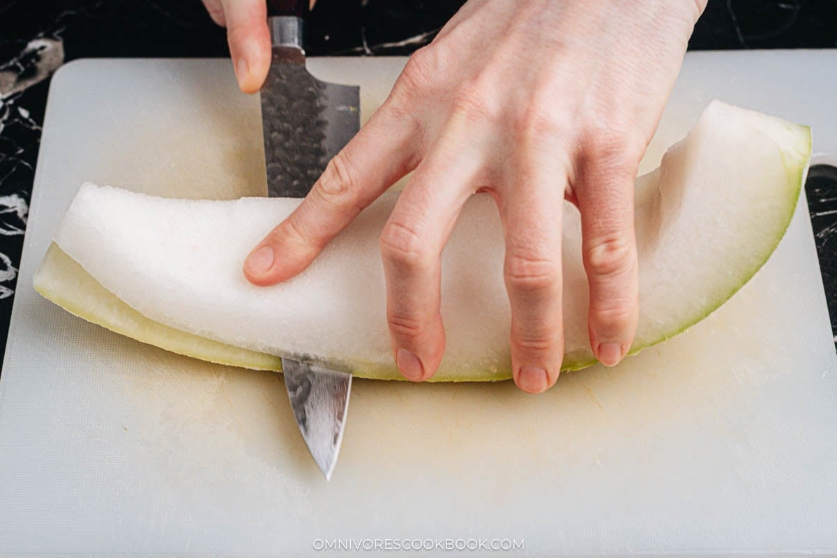 Peeling thick green skin from winter melon