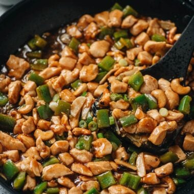 Delicious stir-fried chicken with green peppers in a black skillet.