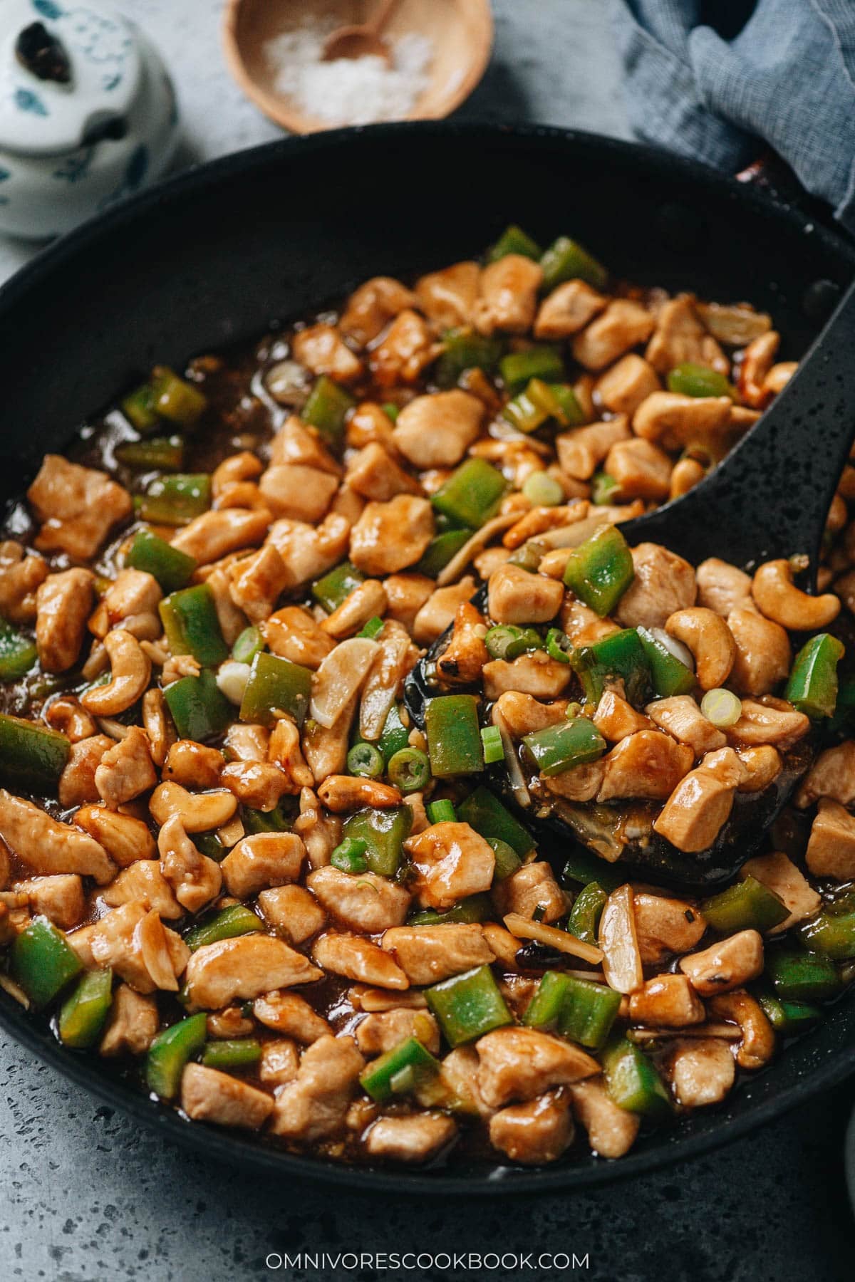 cashew chicken with green peppers in a black skillet.