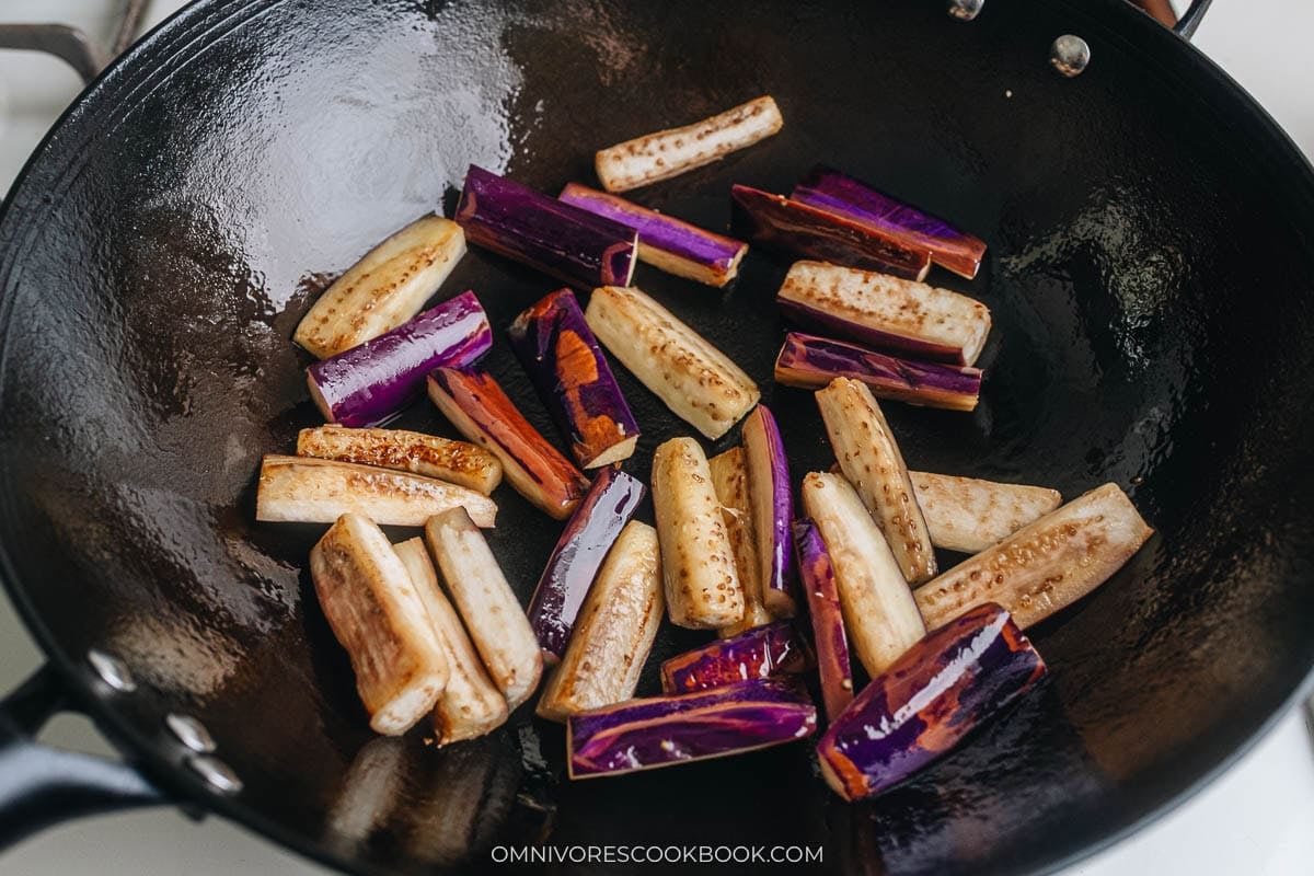 Cooking eggplant pieces in wok