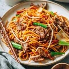 A plate of stir-fried Asian style noodles with chopsticks