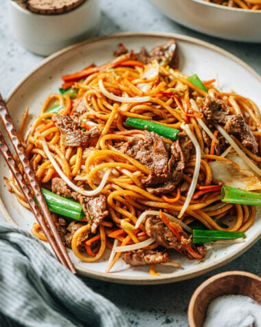 A plate of stir-fried Asian style noodles with chopsticks