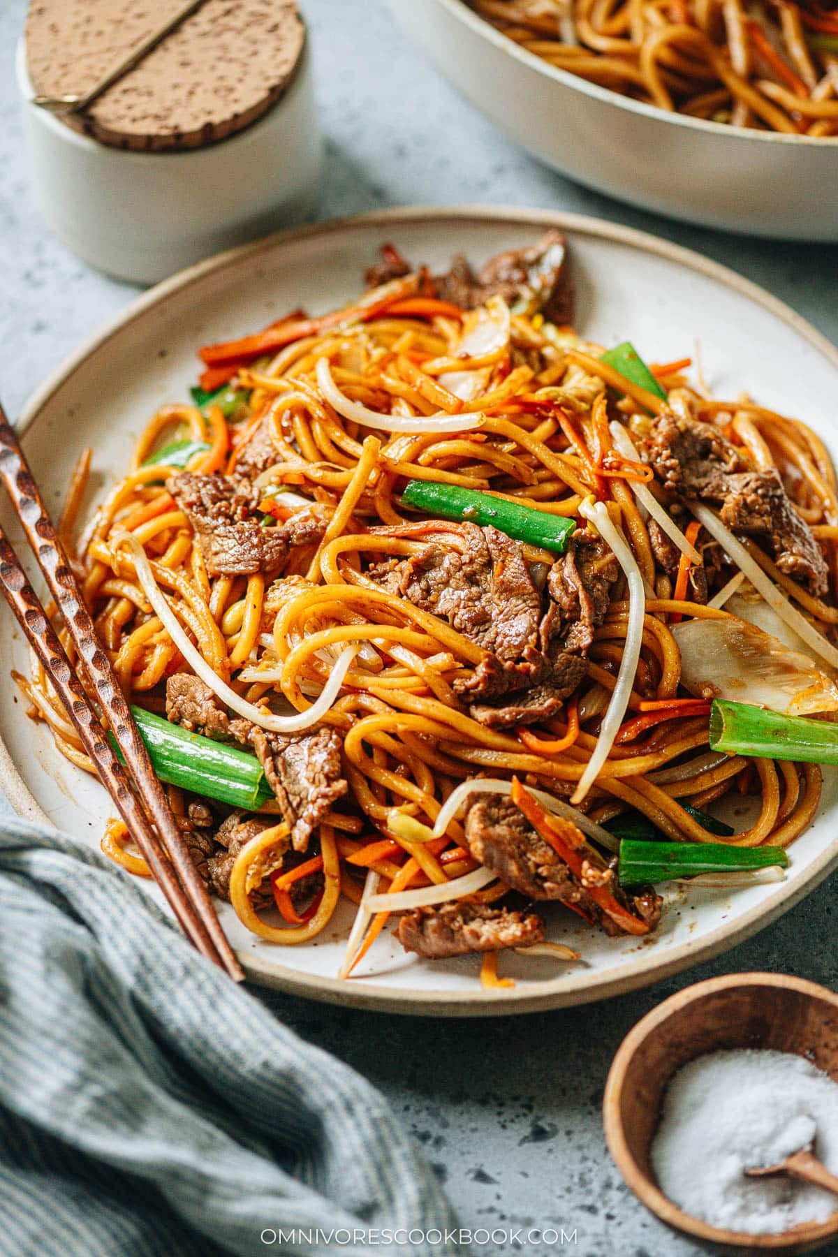 A plate of stir-fried Asian style noodles with chopsticks