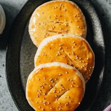 Wife&rsquo;s cake on a plate with golden flaky crust and sesame seeds