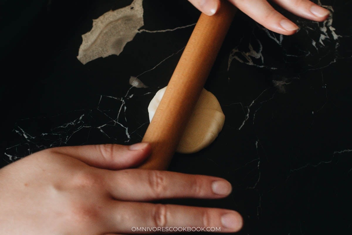 Rolling flattened dough into a smooth pastry wrapper