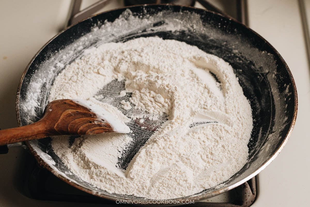 Toasting glutinous rice flour in a pan until lightly golden