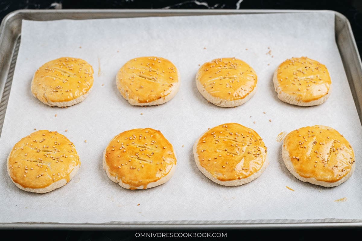 Tray of baked wife&rsquo;s cakes with golden crust and sesame seeds
