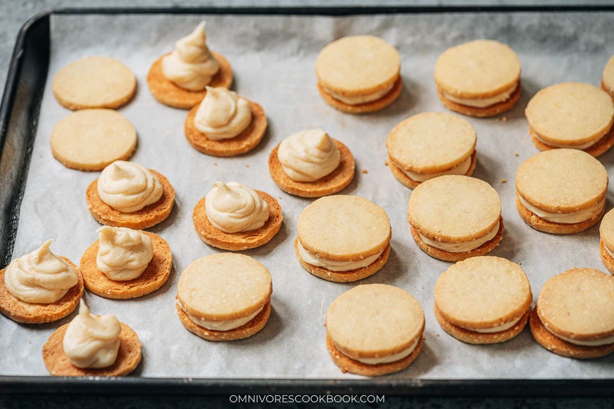 Sesame miso shortbread sandwich on a lined sheet pan, with some unassembled cookies