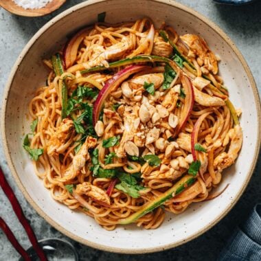 Bowl of spicy Lao Gan Ma chili crisp noodles with shredded chicken, crunchy vegetables, fresh herbs, and peanuts