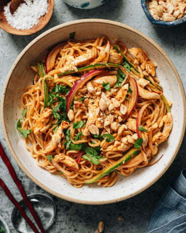 Bowl of spicy Lao Gan Ma chili crisp noodles with shredded chicken, crunchy vegetables, fresh herbs, and peanuts