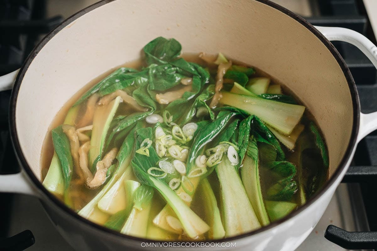 Adding the green parts of the green onion to the broth