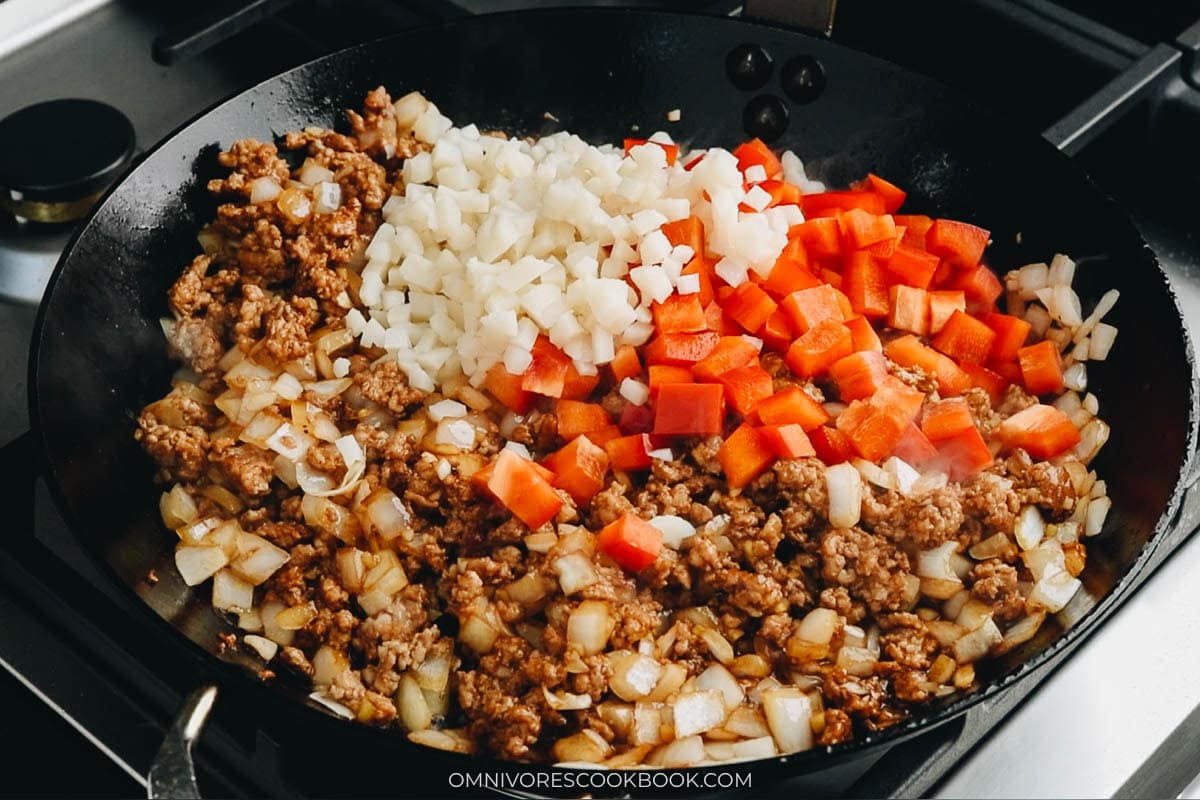 adding the veggies with the pork and cook