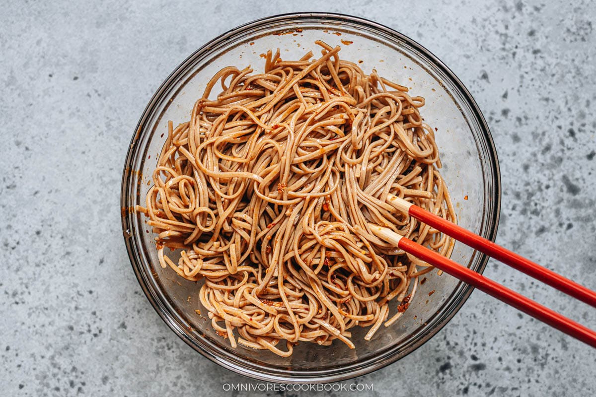 mixing noodles with other ingredients in a bowl