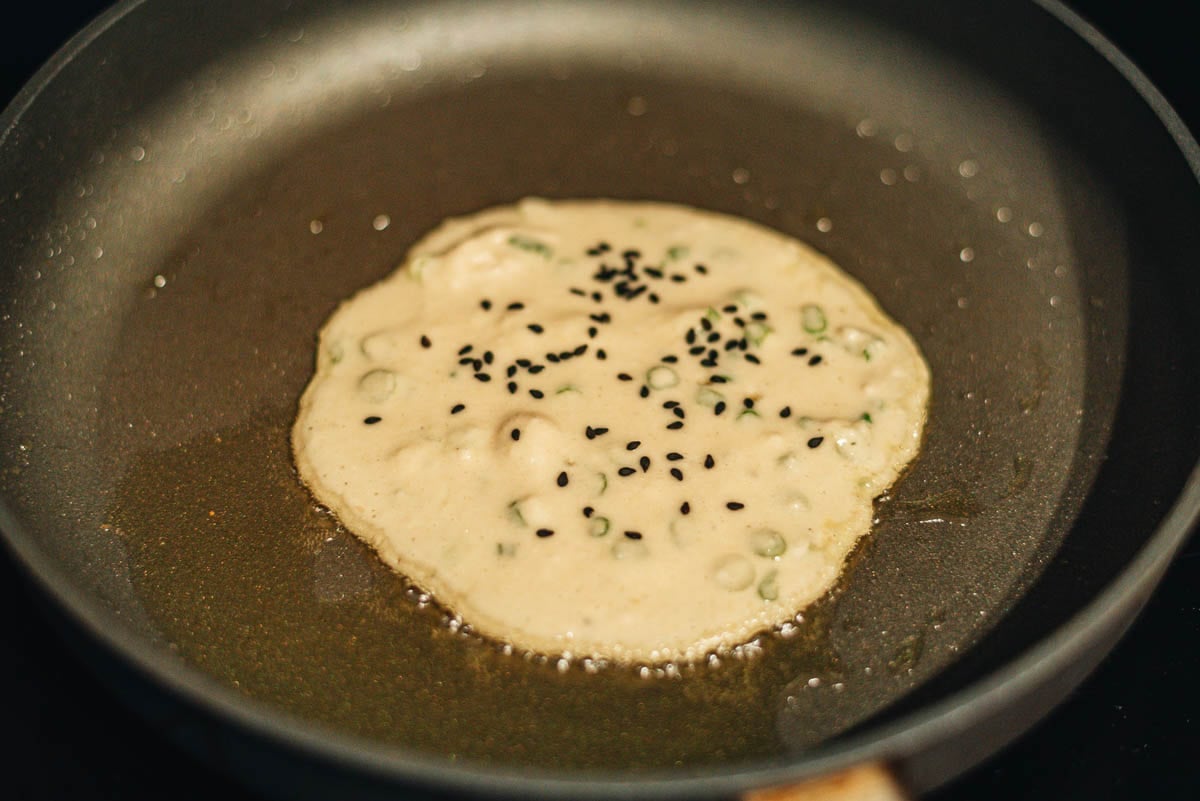 Okara green onion pancakes cooking and browning in a nonstick pan