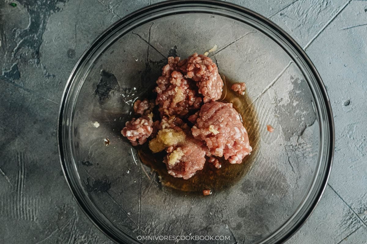 Seasoned ground pork stirred into a sticky paste in a large mixing bowl