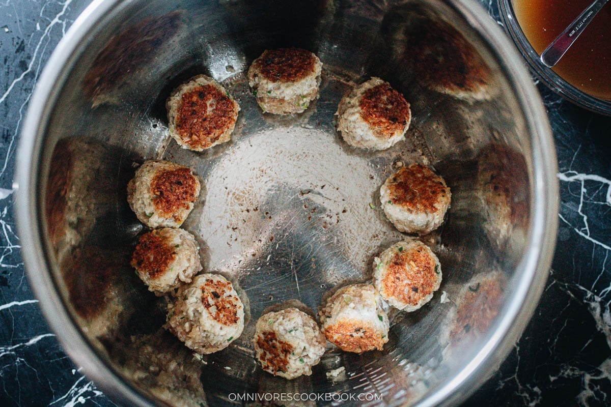 Instant Pot set to saute with oil heating, browning the meatballs