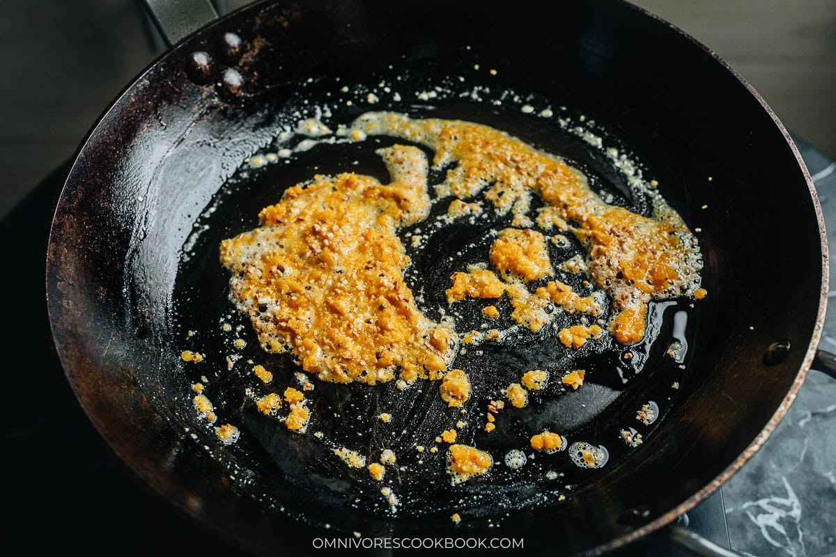 Crumbled salted egg yolk cooking thick and foamy in the pan