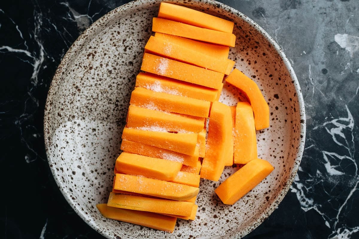 Pumpkin sticks tossed with salt resting in a deep plate to draw out water