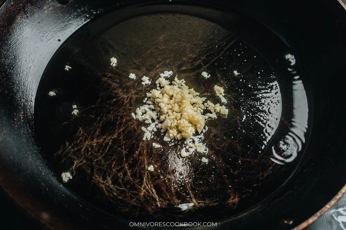 Minced garlic frying in a spoonful of saved oil in the skillet
