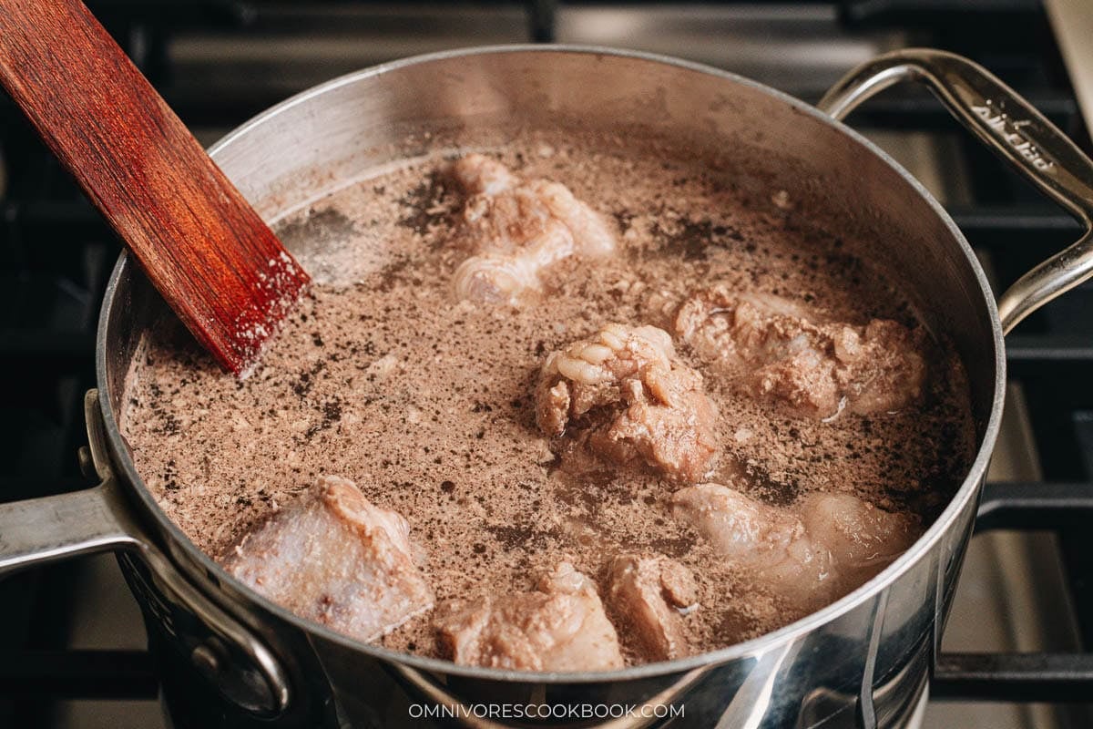 Blanching oxtail in a pot of boiling water to clean it for braising