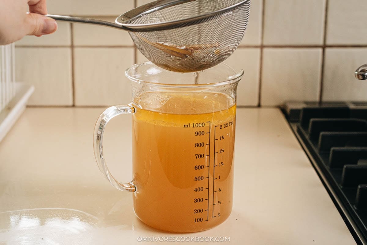 Straining the rich oxtail broth and skimming fat from the surface