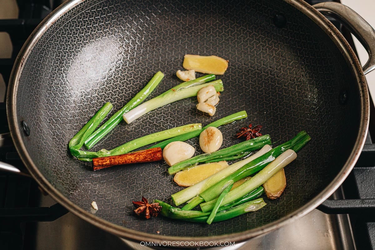 Ginger, garlic, star anise, and cinnamon cooking in oil in a wok