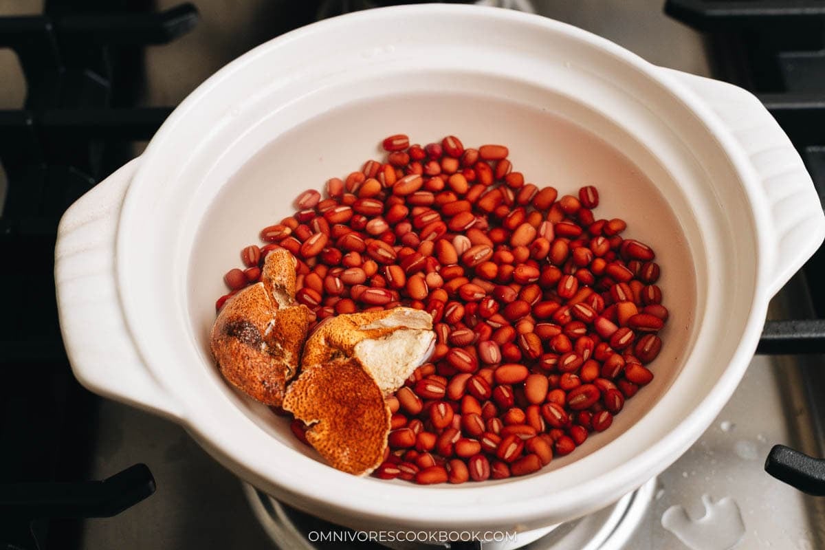 Soaked red beans and dried tangerine peel simmering in a pot of water
