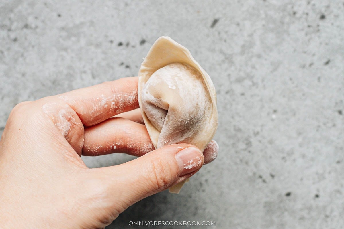 Overlapping and pressing the two side corners of the wonton to seal